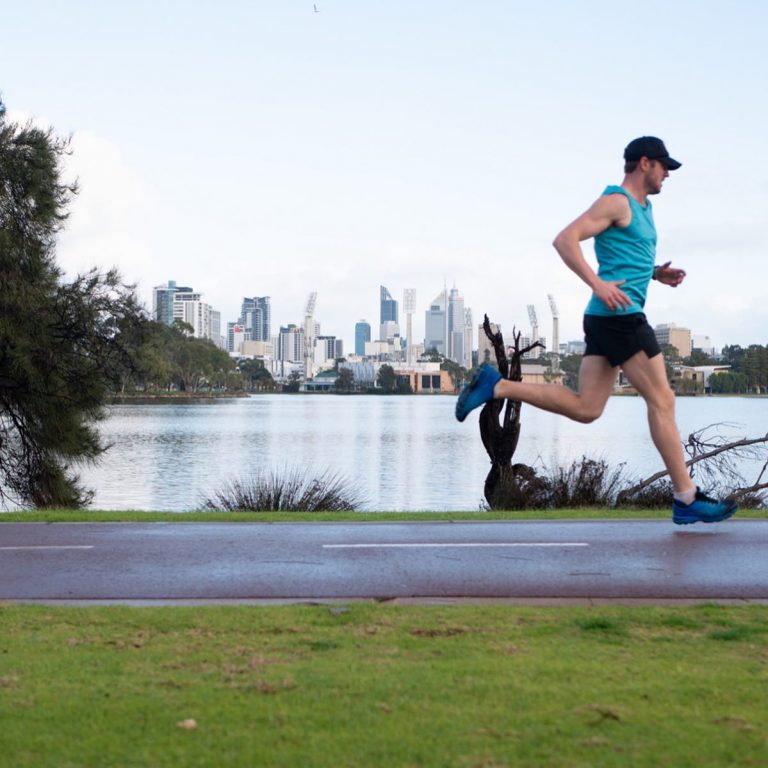 Man running on pathway next to lake on Perth foreshore and skyline